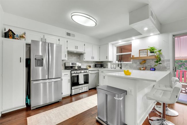Kitchen featuring appliances with stainless steel finishes, open shelves, backsplash, and a peninsula | Image 24