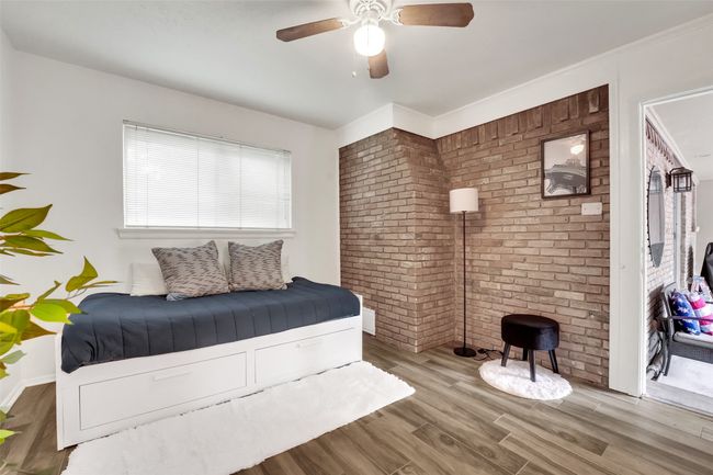 Bedroom with wood finished floors, brick wall, and a ceiling fan | Image 35