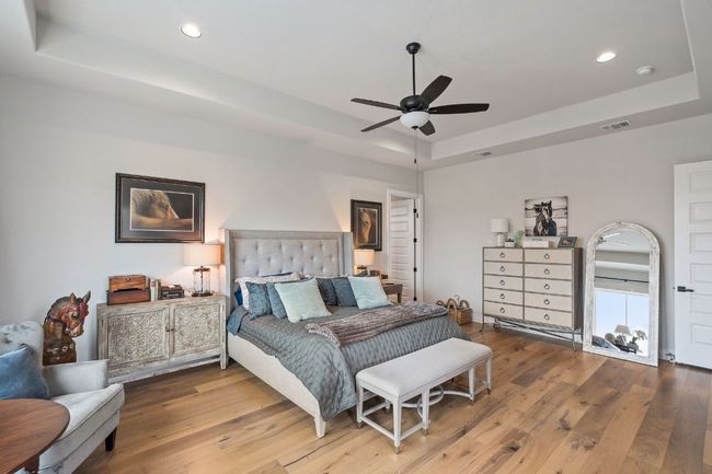 Bedroom with a tray ceiling, wood-type flooring, and visible vents | Image 29
