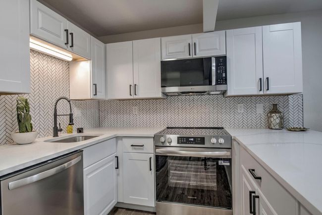 Kitchen featuring white cabinetry, stainless steel appliances, backsplash, and a sink | Image 4