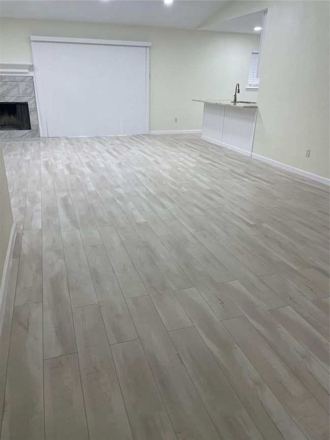 Unfurnished living room featuring light wood-type flooring, baseboards, recessed lighting, a premium fireplace, and a sink | Image 24