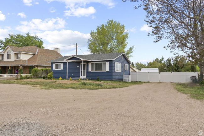 View of front of home with fence, a gate, and dirt driveway | Image 11