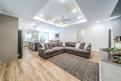 Living room with ceiling fan, light hardwood / wood-style flooring, and a raised ceiling | Image 3