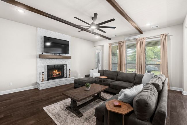 Living area with beamed ceiling, a ceiling fan, a stone fireplace, dark wood-style flooring, and recessed lighting | Image 6
