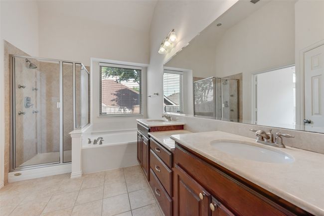 Full bathroom with high vaulted ceiling, double vanity, a bath, a stall shower, and tile patterned flooring | Image 11