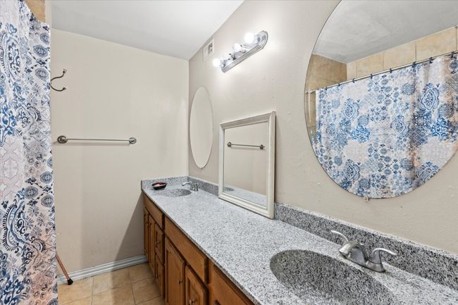 Bathroom with a shower with shower curtain, tile patterned flooring, a sink, and double vanity | Image 9