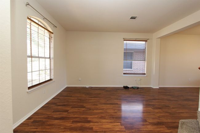 Empty room featuring healthy amount of natural light and wood finished floors | Image 8
