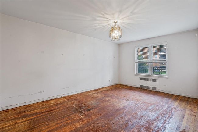 Unfurnished room with radiator heating unit, a chandelier, and wood finished floors | Image 12