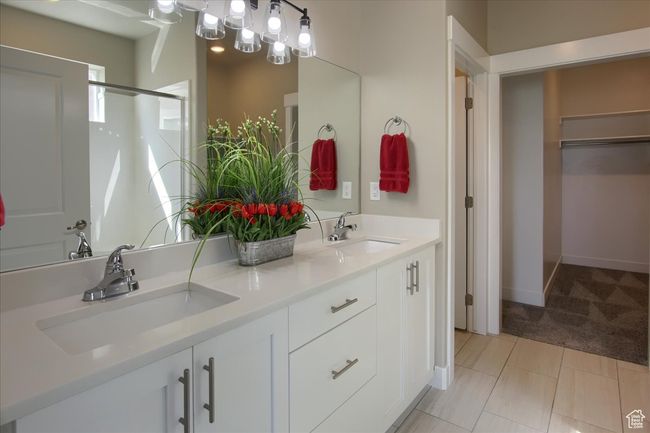 Bathroom featuring a shower with door, a walk in closet, double vanity, and a sink | Image 16