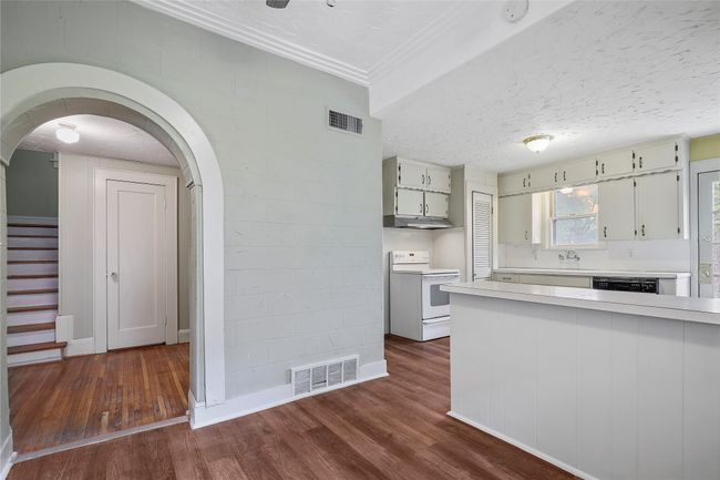 Kitchen with white range with electric stovetop, light countertops, dark wood-style flooring, under cabinet range hood, and ornamental molding | Image 5