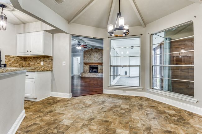 Unfurnished dining area featuring stone finish floors, ceiling fan, a chandelier, and a fireplace | Image 13