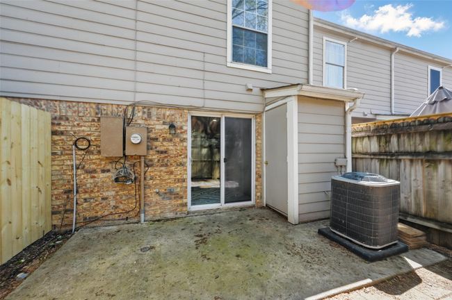 Back of property with brick siding, a patio area, central AC unit, and fence | Image 19