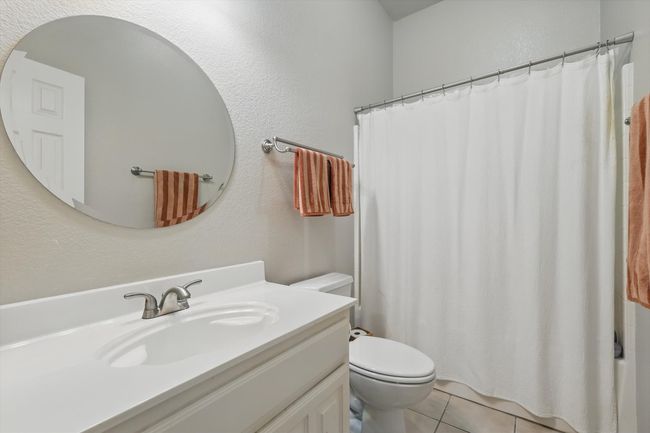 Bathroom with toilet, a textured wall, tile patterned flooring, and vanity | Image 31