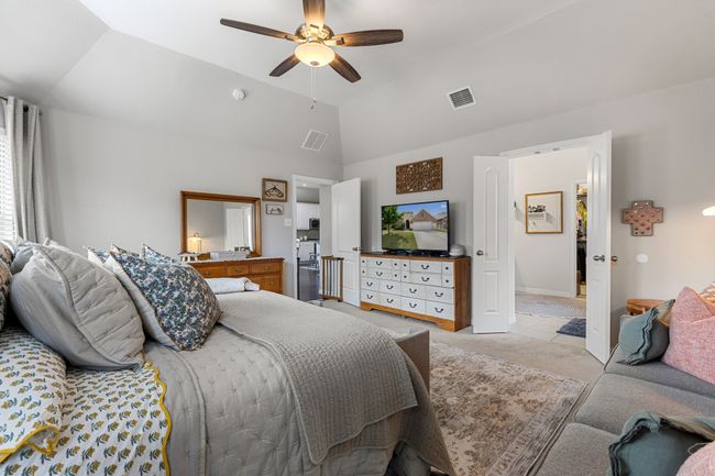 Bedroom with light colored carpet, vaulted ceiling, a ceiling fan, and visible vents | Image 16