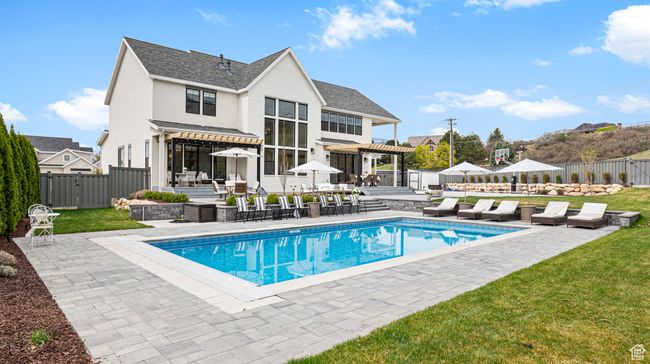 Back of property with a fenced in pool, a pergola, a fenced backyard, a yard, and a patio | Image 52