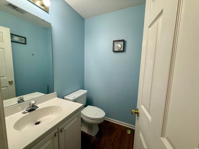 Half bathroom featuring wood finished floors, a textured ceiling, and vanity | Image 6