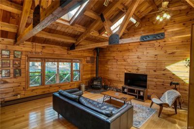 Living room with wood ceiling, light wood-type flooring, and wood walls | Image 2