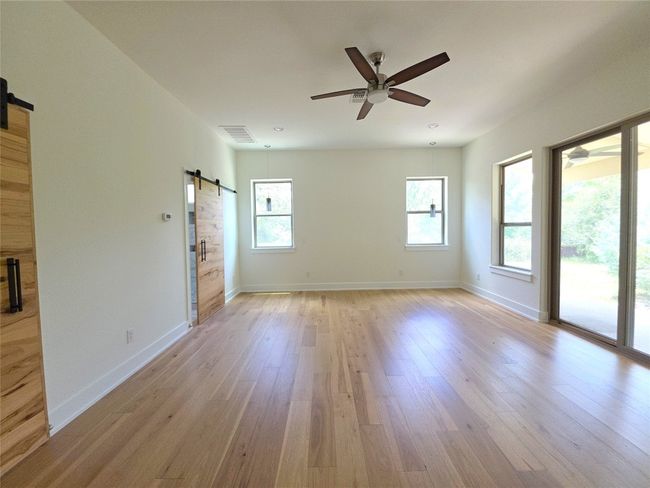 Unfurnished room featuring a barn door, ceiling fan, light wood-style floors, and baseboards | Image 14