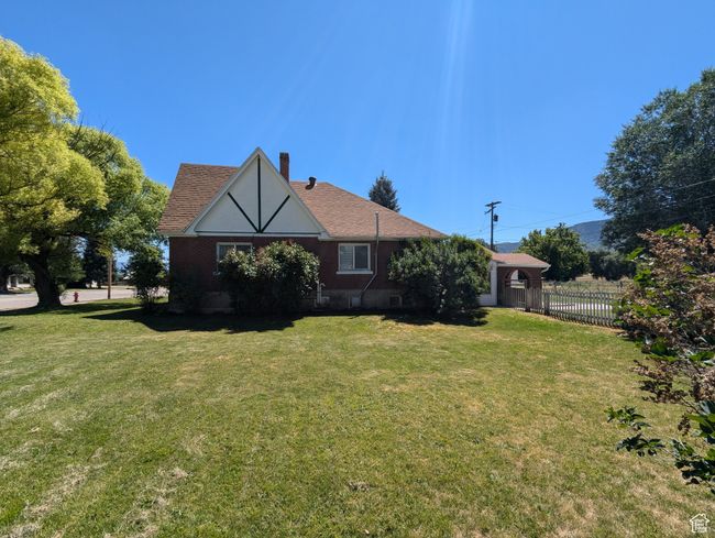 Back of house with a shingled roof, a yard, fence, and a chimney | Image 40