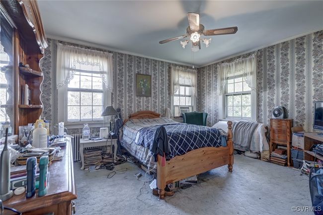 Bedroom featuring wallpapered walls, carpet floors, crown molding, and multiple windows | Image 23