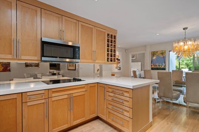 Kitchen featuring stainless steel microwave, a peninsula, light wood-type flooring, a chandelier, and light countertops | Image 6