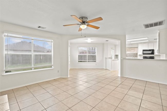 Unfurnished living room featuring a wealth of natural light, visible vents, arched walkways, and a ceiling fan | Image 5