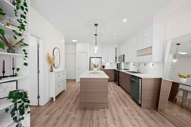Kitchen with modern cabinets, a sink, light countertops, white cabinets, and appliances with stainless steel finishes | Image 7