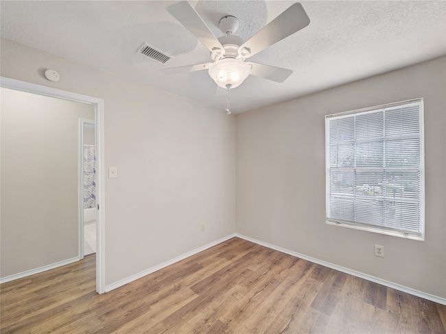 Spare room with light wood finished floors, baseboards, a smoke detector, and a ceiling fan | Image 18