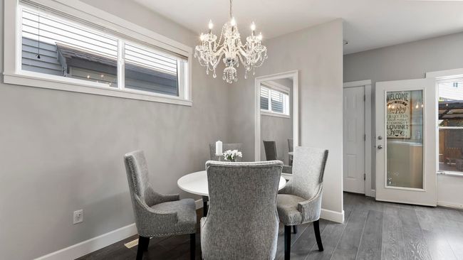 Dining space with wood finished floors, a healthy amount of sunlight, and a notable chandelier | Image 8