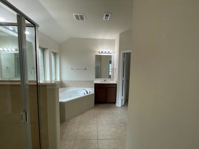 Full bath featuring a bath, a stall shower, vanity, tile patterned flooring, and vaulted ceiling | Image 15