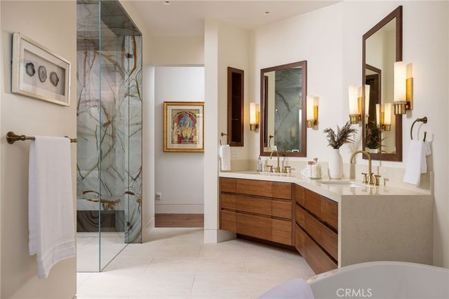 The spa-inspired primary bath features quartzite surfaces, steam shower, freestanding jacuzzi tub, and custom walnut cabinetry. | Image 16