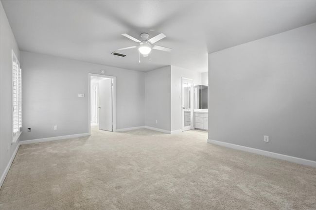 Primary bedroom featuring baseboards, light carpet, visible vents, and ceiling fan | Image 19