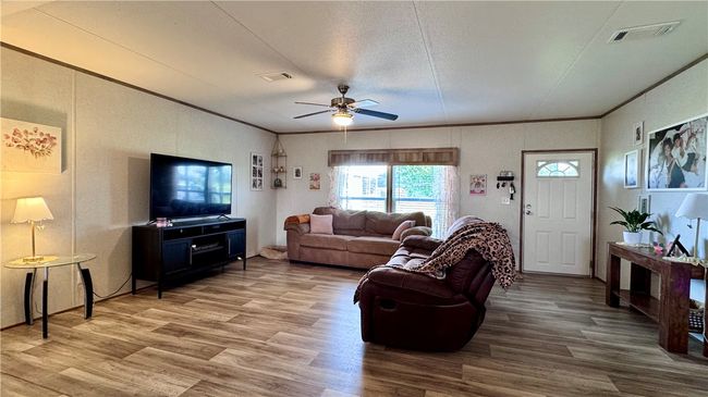 Living area with ceiling fan, wood finished floors, a textured ceiling, and ornamental molding | Image 14