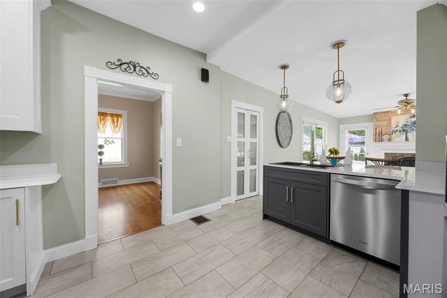 Kitchen featuring stainless steel dishwasher, light countertops, ceiling fan, pendant lighting, and gray cabinetry | Image 7
