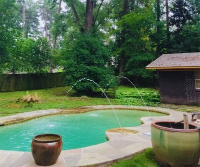 View of swimming pool with pool water feature and a lawn | Image 1