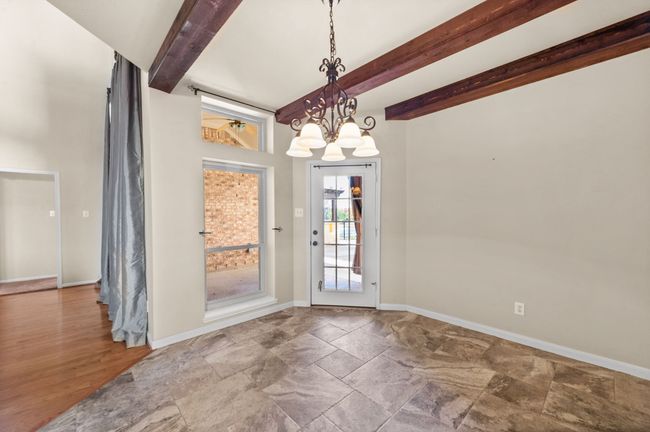 Unfurnished dining area with beamed ceiling, stone finish flooring, and a chandelier | Image 11