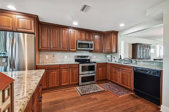Solid wood cabinets, backsplash, and stainless steel appliances. | Image 12