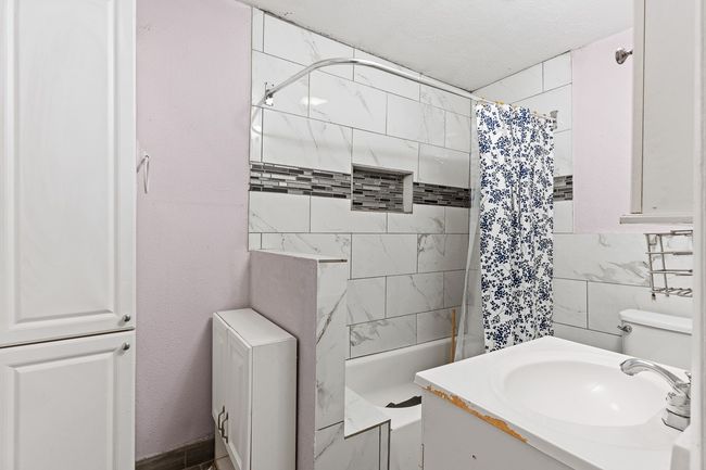 Full bathroom featuring a shower with curtain, vanity, and tile walls | Image 36