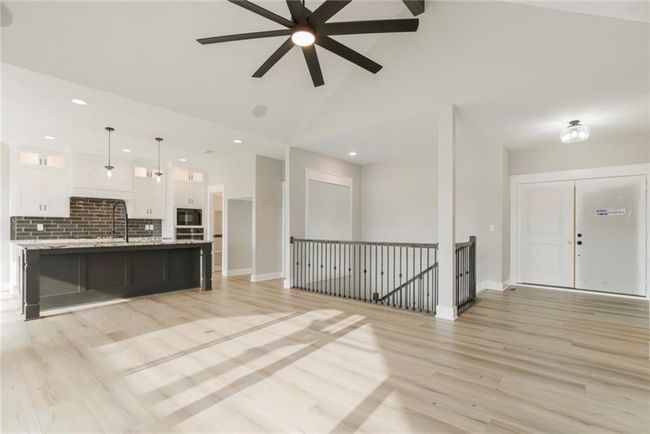 Kitchen with white cabinets, light wood-type flooring, decorative backsplash, a ceiling fan, and glass insert cabinets | Image 7