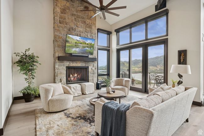 Living room with a ceiling fan, high vaulted ceiling, a fireplace, and wood finished floors | Image 12
