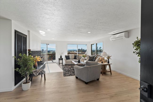 Living room featuring a wall mounted air conditioner, light hardwood / wood-style floors, and a textured ceiling | Image 10