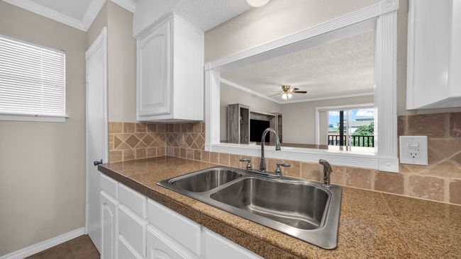 Kitchen with ceiling fan, decorative backsplash, sink, and white cabinetry | Image 11