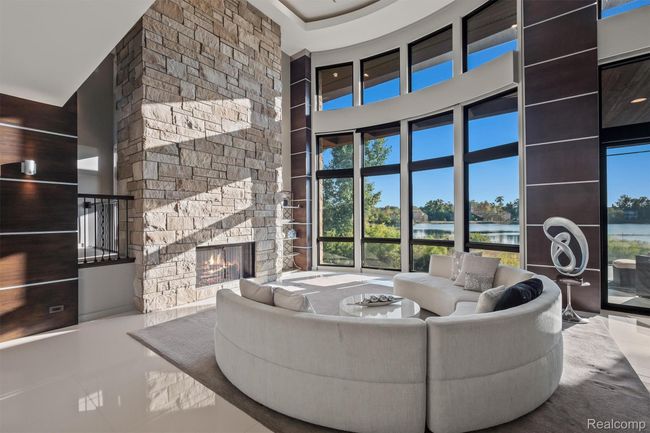 Tiled living area with a water view, a stone fireplace, healthy amount of natural light, and a towering ceiling | Image 8