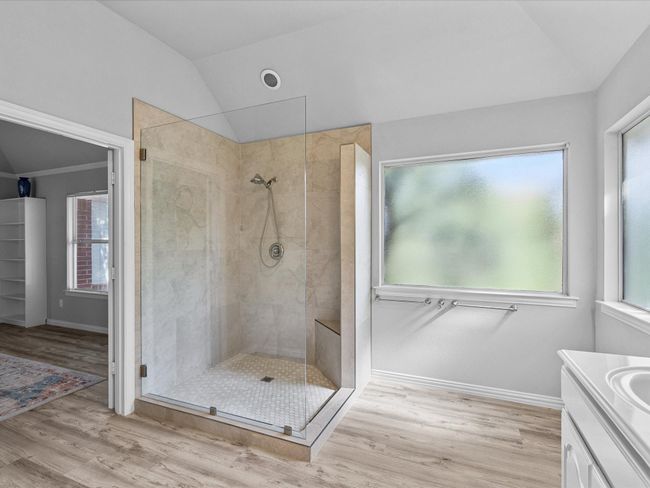 Master full bath featuring lofted ceiling, tiled shower, double-sink vanity, laminated floors and plenty of natural light | Image 23