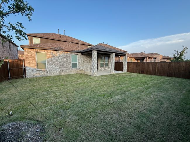 Rear view of house featuring a patio area, roof with shingles, and brick siding | Image 23