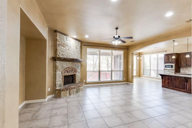 Unfurnished living room with a stone fireplace, baseboards, living room featuring a fireplace, a ceiling fan, and light tile patterned floors | Image 9