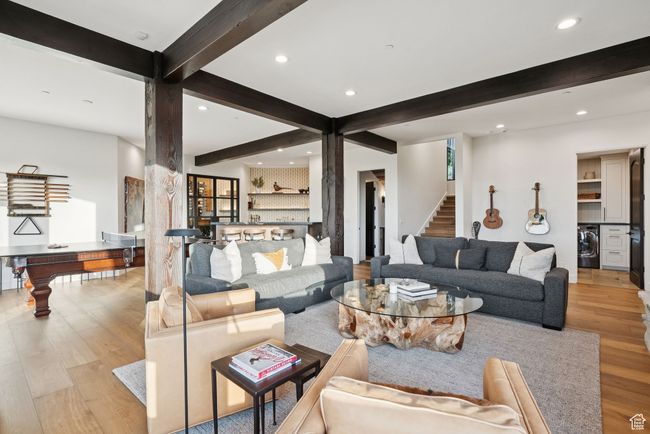 Living room featuring washer / dryer, beam ceiling, wood finished floors, recessed lighting, and stairs | Image 46
