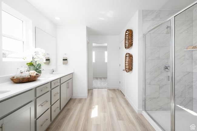 Bathroom with double vanity, a shower stall, wood finished floors, and baseboards | Image 13