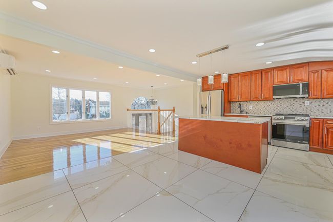 Kitchen with a wall mounted air conditioner, decorative light fixtures, a kitchen island, stainless steel appliances, and decorative backsplash | Image 17