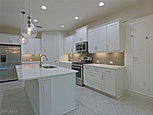 Kitchen featuring appliances with stainless steel finishes, a sink, recessed lighting, backsplash, and light countertops | Image 12